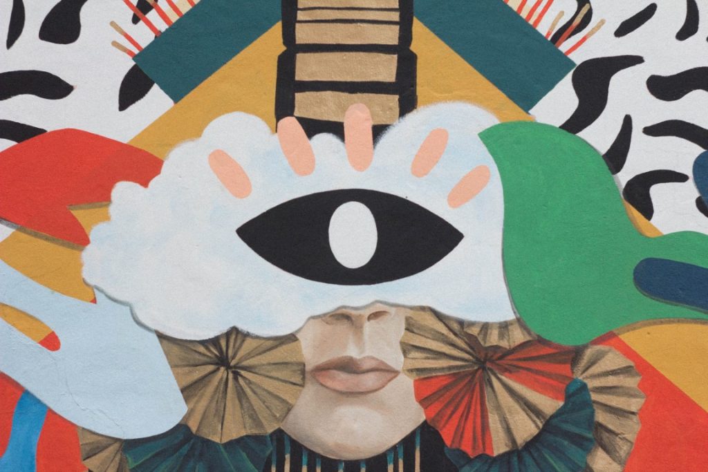 Picture of an art piece that looks like a collage of different patterns and iconography. Notably a single eye is at the center.
